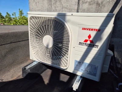 Een Mitsubishi 3,5 kW buitenunit op plat dak in de zon