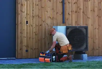 Monteur installeert warmtepomp voor houten wand buiten