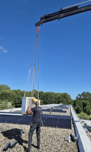 Monteur plaatst warmtepomp op het dak