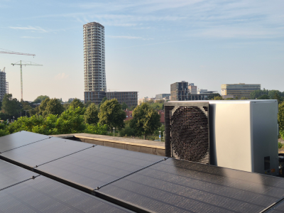 Daikin EBLA11 warmtepomp met koelfunctie op Amsterdams dak met zonnepanelen en wolkenkrabber op achtergron