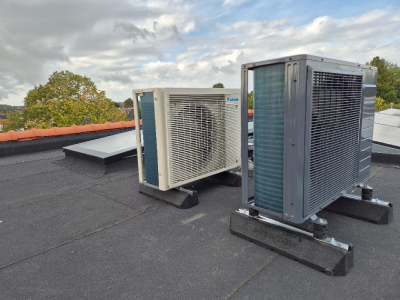 Hybride intergas warmtepomp met koelfunctie naast een Daikin airco op een plat dak