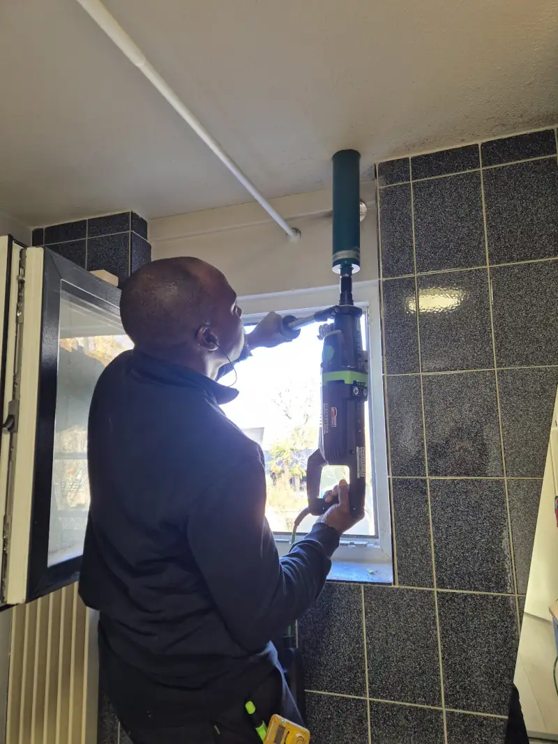 Monteur boort gat door plafond van onderaf